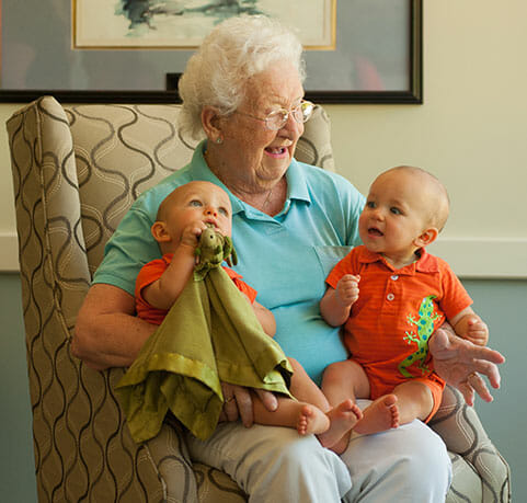 senior woman holding two small babies