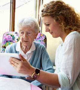 Senior woman being shown how to use a tablet by an employee