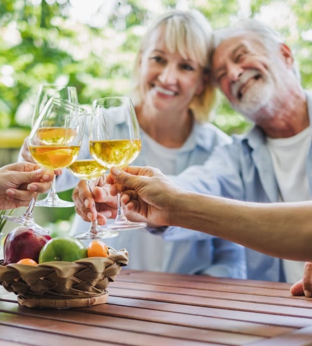 Senior couples cheer wine glasses during dinner