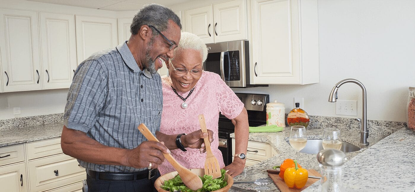 Senior couple preparing salad in their kitchen